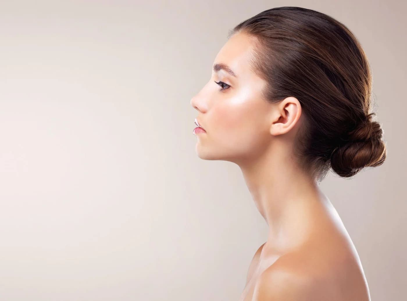 Adult woman in side profile against a warm neutral studio background